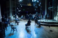 Actors sat on chairs on stage and others stood at back of stage