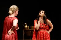 Two actors performing, both wearing red dresses