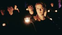 Female actor stood on stage holding a candle