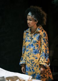 Actress stood on own wearing a yellow and blue floral dress and headband