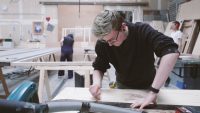 Male scenic art student marking wood in workshop