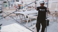 Student wearing hardhat working on set construction in workshop