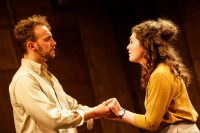 Male and female actors on stage facing each other and holding hands