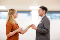 Female and male actor stood looking at each other holding a glass each