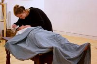 Students in rehearsal, one lying down, the other mopping her brow