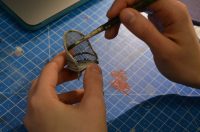 Close up of hands holding small paintbrush and minature chair