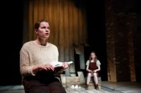 Actors on stage, one reading a book