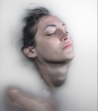 Female with head sticking up from bath of milk