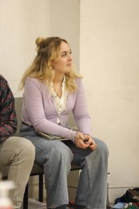 Female sat in chair holding pen and books on her lap