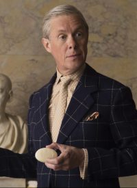 Still of Alex Jennings as Edward VIII stood up holding a bar of Floris soap