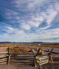 Deserted road with fence in the foreground and mountains in the background