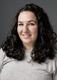 Headshot of smiling woman with shoulder length curly black hair