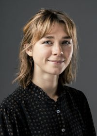 Headshot of woman with short blonde hair and a fringe in a black shirt