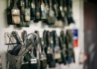 Image of lots of paintbrushes hung up and a whisk in a pot