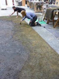 Artists knelt down painting floor