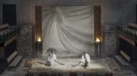 Set design for Pericles, two figures sitting on sand with flaming torches nearby