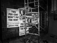 Black and white image of posters on a wall with pictures of Maggie Thatcher and scaffolding in front