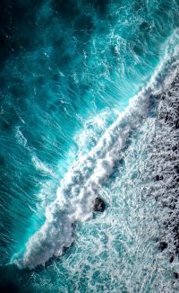 Waves crashing against the shore, striking blues and sharp white colours