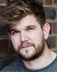 Headshot of male with dark blonde hair and beard