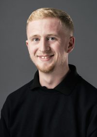 Headshot of blonde man looking directly at the camera and smiling