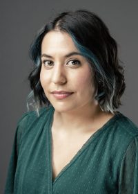 Headshot of woman with short black curled hair with blue higlights