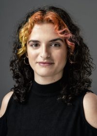 Headshot of woman with curly black hair and orange highlights