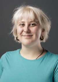 Headshot of woman with short blonde hair in a turquoise top