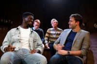 Four actors sat in chairs on stage