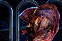 Actor on stage wrapping large patterned scarf around herself