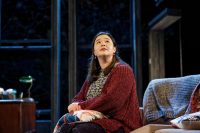 Actor sat on sofa on stage, looking upwards