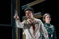 Two actors on stage, one with blood stained face and shirt