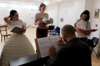 Actors singing in rehearsals, with male sat at piano